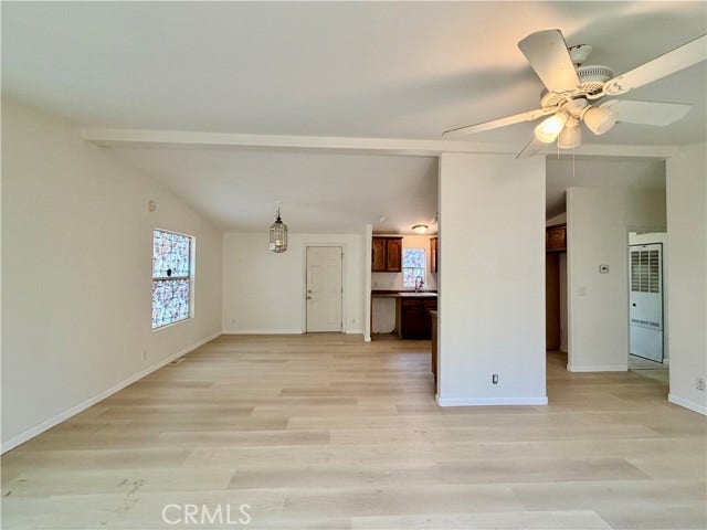 open living space with neutral finishes and a ceiling fan.