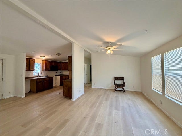 bright living room with a ceiling fan and light toned flooring.