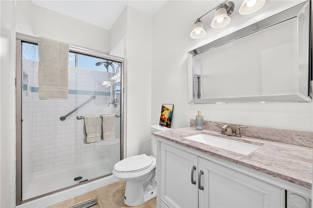 Well-appointed bathroom features a large vanity, tub/shower combination, and bright contemporary finishes.