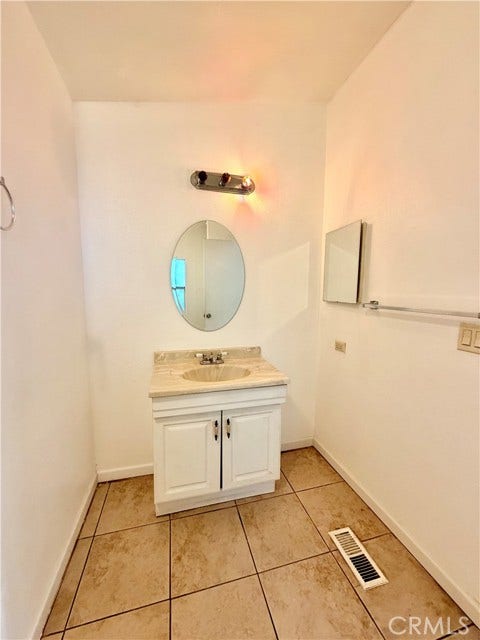 bathroom vanity with cabinet storage and a round mirror.
