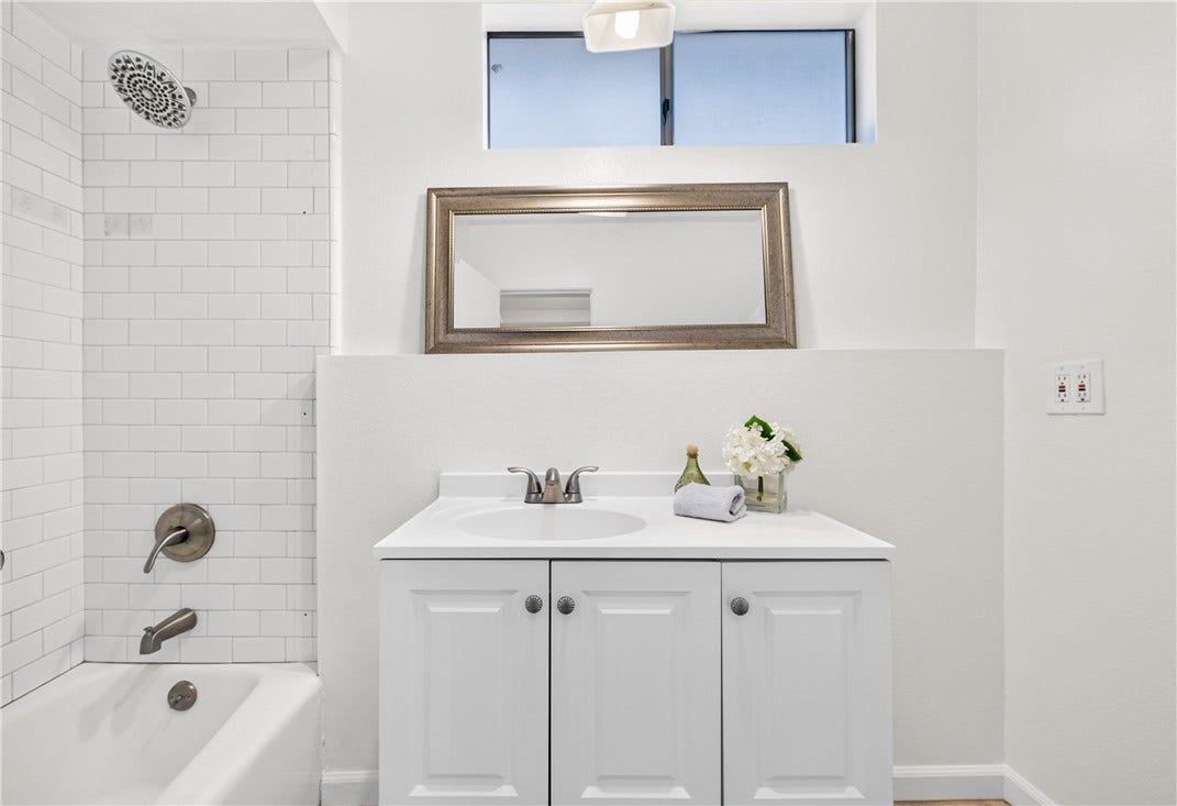 Bright bathroom features a clean vanity, tub/shower combination, and modern tile detailing.