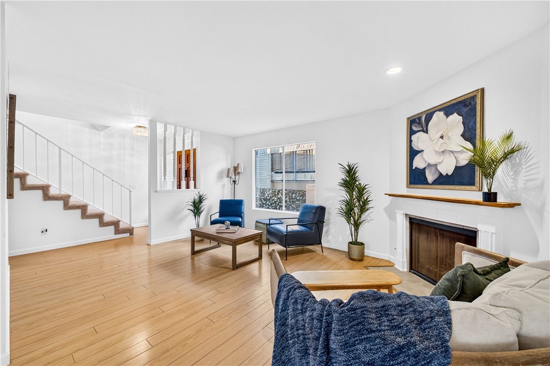 Spacious living area showcases warm wood flooring, fireplace, and abundant natural light.