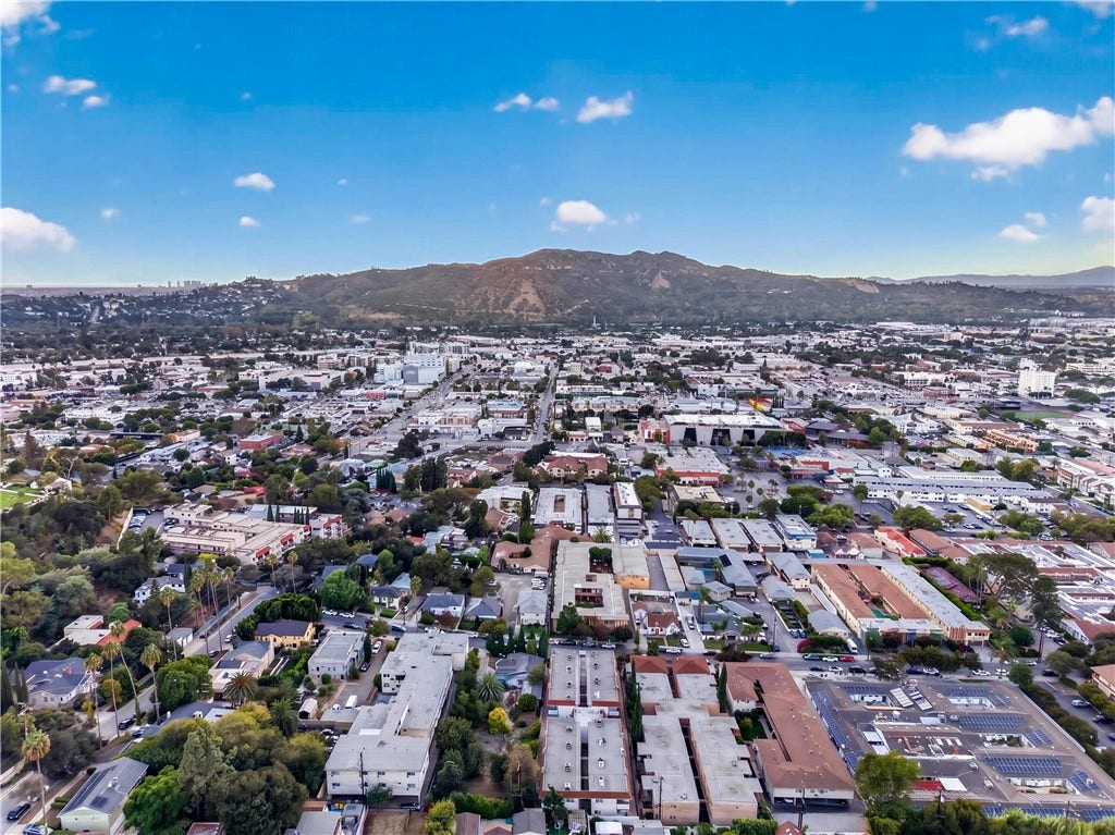 Wide-angle aerial view highlights the vibrant Southern California setting and surrounding mountain terrain.