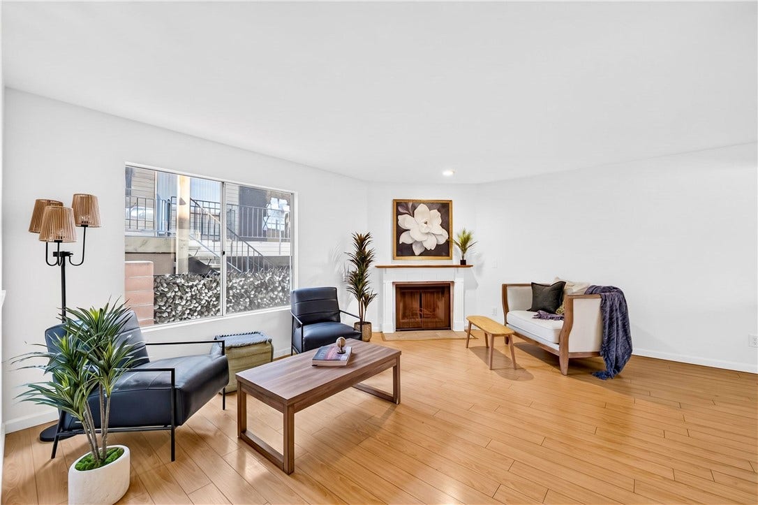 Light-filled living room features beautiful wood flooring, fireplace, and generous entertaining space.
