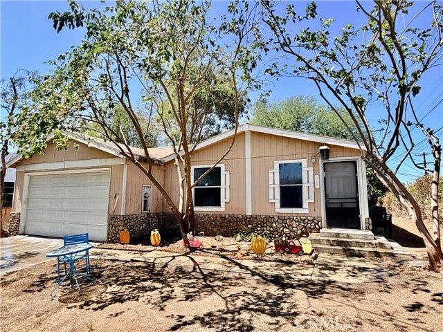 single story home with an attached garage and mature trees