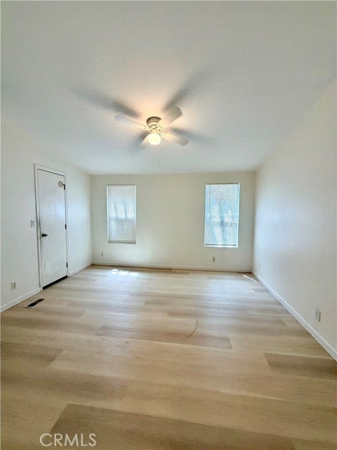 spacious masterroom with multiple windows and a ceiling fan.