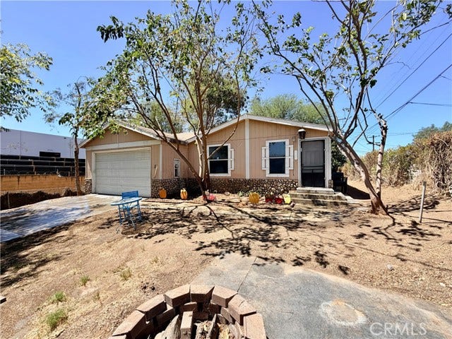 wide front view showcasing the driveway and spacious front yard