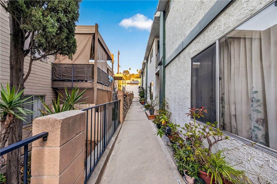 Resident entry walkway offers a charming approach surrounded by established landscaping.